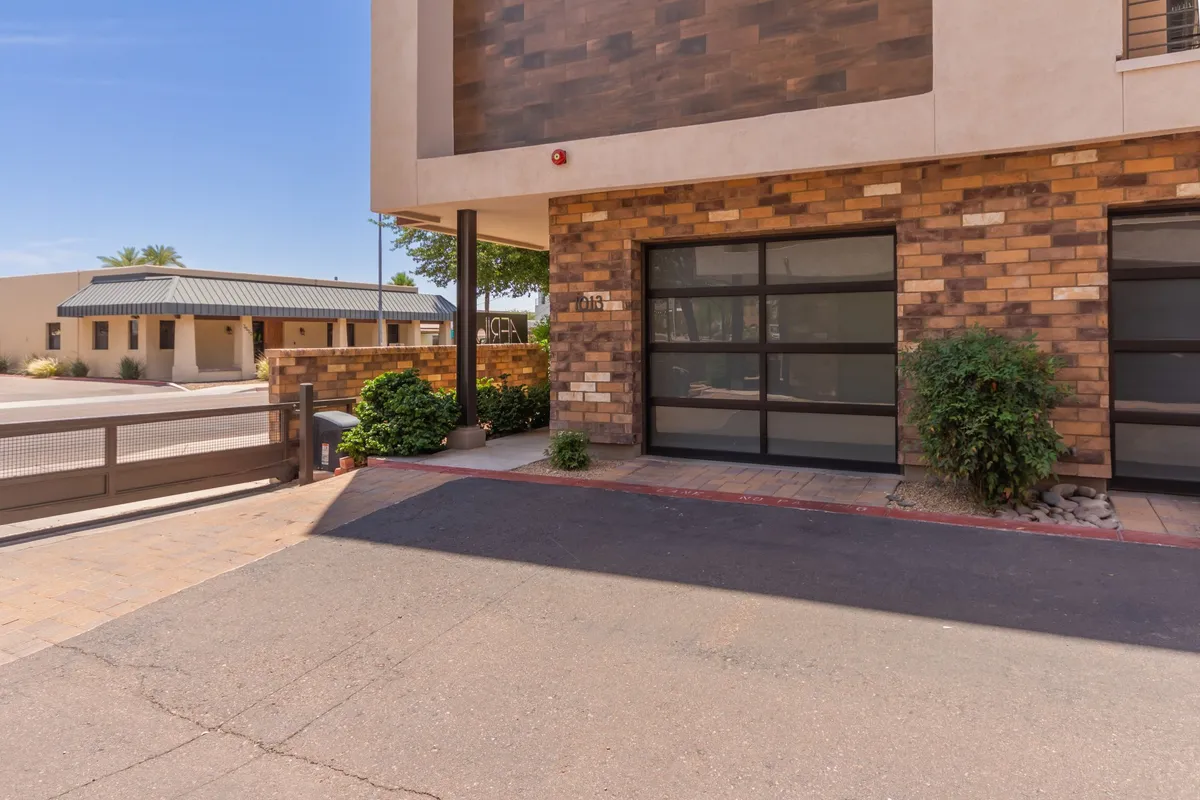 A striking view of the property’s modern architectural design, featuring a blend of brick and stone façade, a large glass garage door, and landscaped greenery. The image provides a clear sense of arrival and the impressive curb appeal of the home.