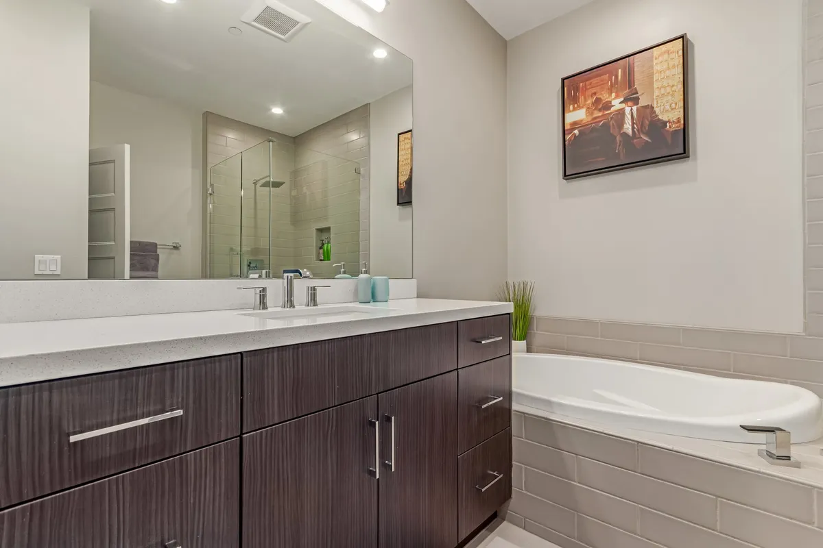 A spa-inspired bathroom with double vanity sinks, a walk-in shower, a bathtub, and framed artwork. The clean, upscale design creates a serene environment for both relaxation and daily routines.