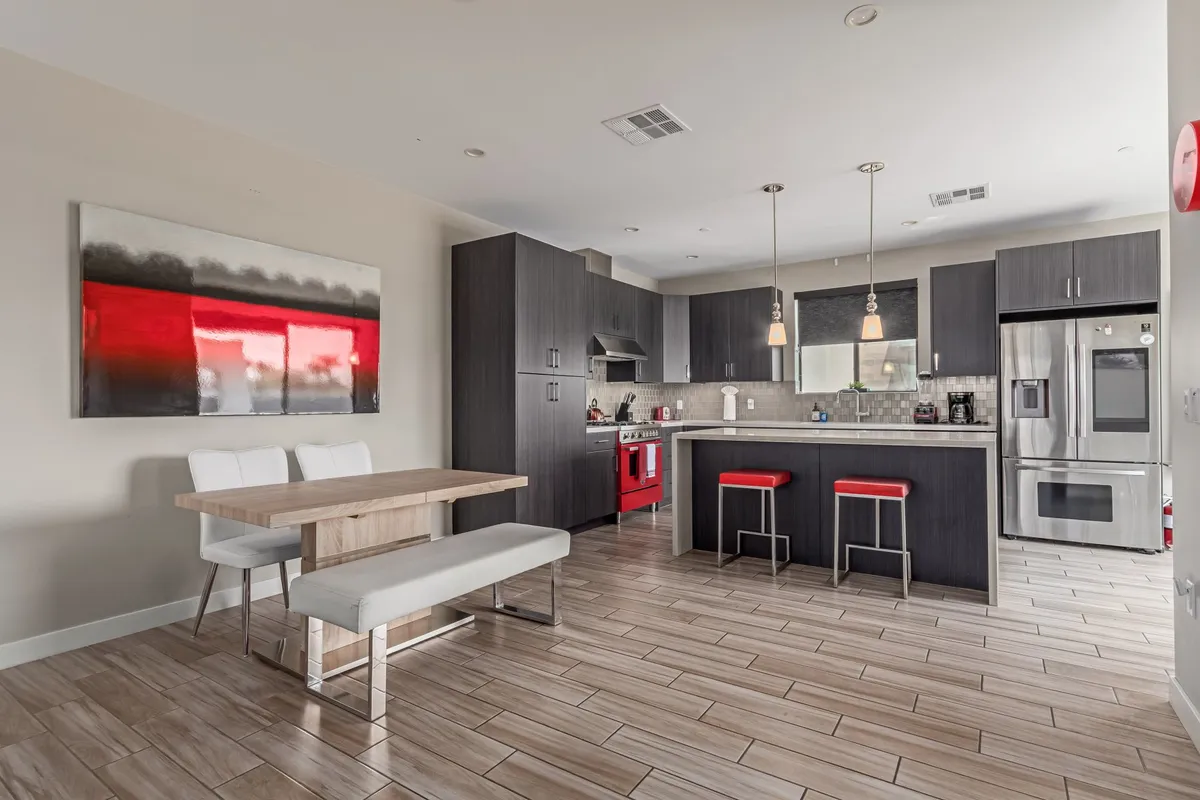 An inviting kitchen-dining area showcasing a large kitchen island, a cozy dining table, and contemporary artwork. The open layout is highlighted by natural light, emphasizing the ease of hosting and the seamless flow between cooking and dining spaces.